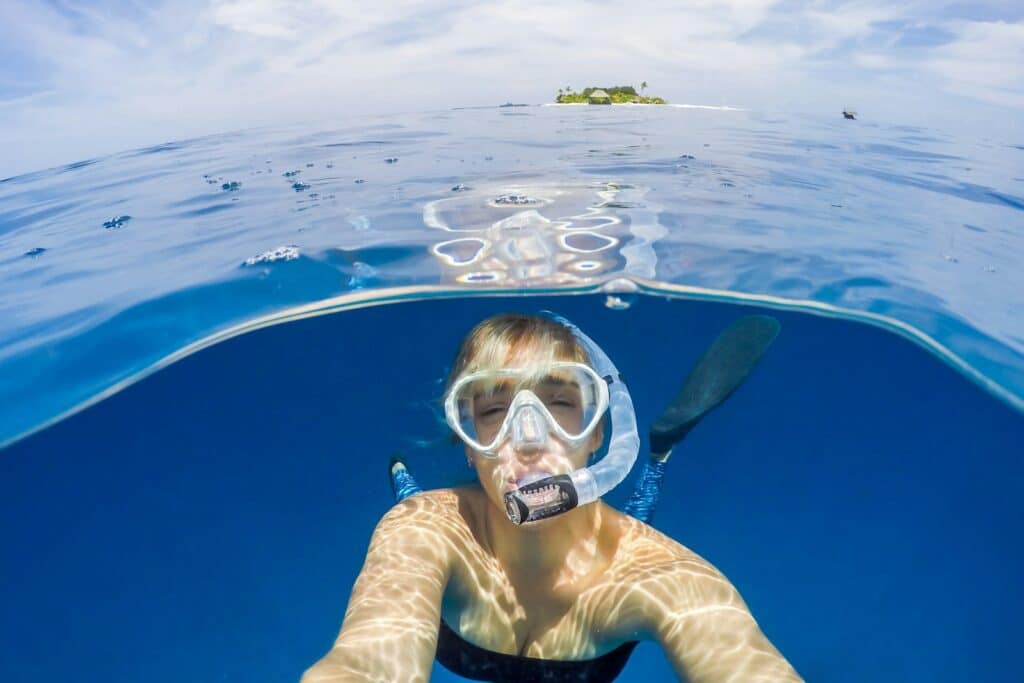 A woman snorkelling in clear turquoise water, viewed from above