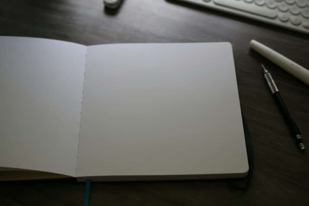 An open field notebook with handwritten notes on a wooden desk