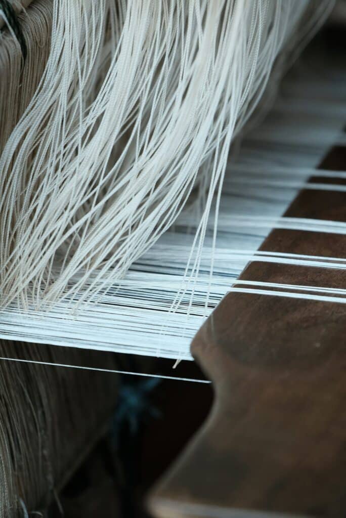 Close-up of hands weaving traditional cloth on a wooden loom in Kelantan